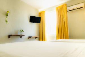 Schlafzimmer mit einem Bett und einem Fenster mit gelben Vorhängen in der Unterkunft Caribe Princess in Chetumal