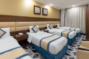 una habitación de hotel con 3 camas. en Ehdaa Hotel en La Meca
