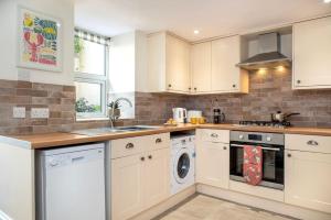 a kitchen with white cabinets and a washer and dryer at Cosy Cottage rural village near Tavistock/sleeps 4 in Bere Alston