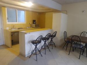 a kitchen with a bar with chairs and a table at Puerto mar 2 in Acapulco