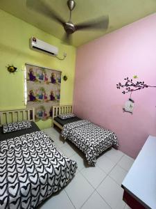a room with two beds and a ceiling fan at Homestay Dferry Jerantut Fully Aircond in Jerantut