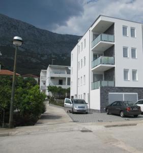 un edificio bianco con auto parcheggiate in un parcheggio di Apartments Lara a Drvenik