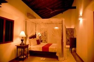een slaapkamer met een hemelbed en een tafel met een lamp bij Villa 386 in Ahungalla