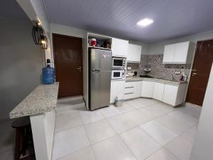 a kitchen with white cabinets and a stainless steel refrigerator at Casa Saltos del Guiara in Salto del Guairá