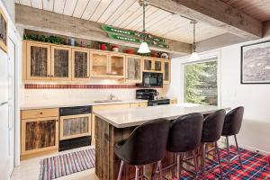a kitchen with wooden cabinets and black bar stools at Chateau Eau Claire Unit 1, Stylish Condo Overlooking the River, Walking Distance to Downtown in Aspen
