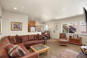 a living room with a brown leather couch and a kitchen at Silverglo Condominiums Unit 308, Expansive 4 BD Condo, Walking Distance to Town with Pool Access in Aspen