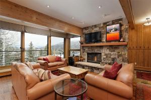 a living room with leather furniture and a stone fireplace at Durant Unit C5, Condo with Bonus Den, Air Conditioning, and Spectacular Views in Aspen
