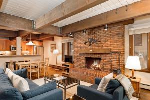 sala de estar con sofás azules y chimenea de ladrillo en Cottonwoods Unit 1F, Stylish Condo with Excellent West End Location, Wood-Burning Fireplace, en Aspen