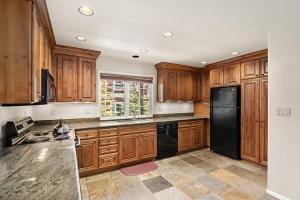 a kitchen with wooden cabinets and a black refrigerator at Alpenblick 13, Spacious Townhouse with Lots of Great Features, Close to Downtown in Aspen