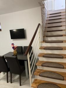 a dining room with a table and stairs with a television at Vila F&C in Braşov