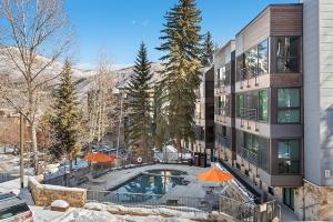 an apartment building with a swimming pool and orange umbrellas at Durant Unit D5, Luxury Condo with Beautiful Furnishings, Great Views, and Central A/C in Aspen
