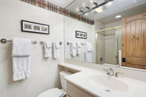 a bathroom with a sink and a toilet and a mirror at Fasching Haus Unit 8, Deluxe Condo w/ A/C, Private Deck, 2 Blocks to Downtown in Aspen