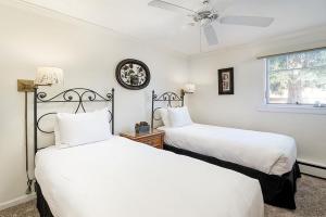 two beds in a white room with a ceiling fan at Fasching Haus Unit 8, Deluxe Condo w/ A/C, Private Deck, 2 Blocks to Downtown in Aspen
