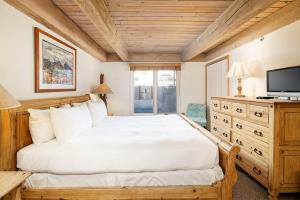 a bedroom with a white bed and a television at Chateau Eau Claire Unit 8, Riverfront Condo, Walking Distance to Town in Aspen