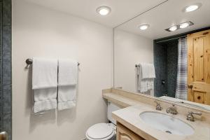 a bathroom with a sink and a toilet and a mirror at Chateau Eau Claire Unit 8, Riverfront Condo, Walking Distance to Town in Aspen +10 photos