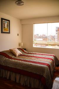 ein Schlafzimmer mit einem großen Bett und einem großen Fenster in der Unterkunft Aura Apartamento Cusco in Cusco