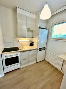a kitchen with white cabinets and a white refrigerator at Viihtyisä tilava kaksio in Valkeakoski