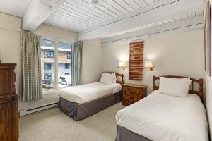 Un dormitorio con dos camas y una ventana. en Chateau Roaring Fork Unit 29, Sunny, Corner Condo with River Views, en Aspen