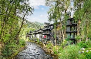 a river in front of a building with trees at Chateau Roaring Fork Unit 29, Sunny, Corner Condo with River Views in Aspen