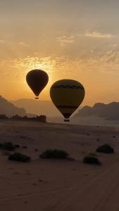 two hot air balloons flying over the desert at sunset at Desert star camp in Wadi Rum