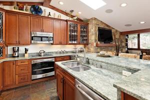 a kitchen with wooden cabinets and a sink at Fasching Haus Unit 5, Deluxe Condo with Great Natural Light & Amazing Location in Aspen