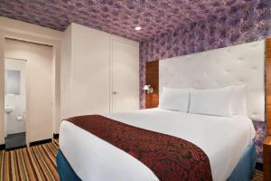 a bedroom with a large bed with a purple wall at Night Hotel Broadway in New York