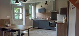 a kitchen with a table and a refrigerator and a sink at La Clé des champs in Luchy