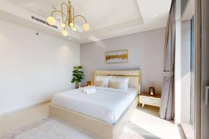 a bedroom with a large white bed and a chandelier at Paramount, Midtown - Locations in Dubai