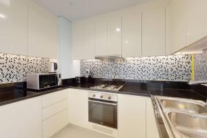 a kitchen with white cabinets and a stove top oven at Paramount, Midtown - Locations in Dubai