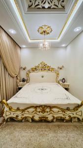 Cama de oro en habitación con lámpara de araña en Maison Fathallah, en Mahdia