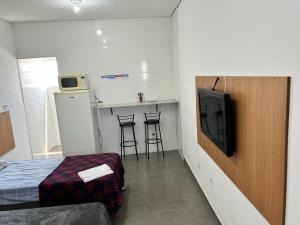 a room with a bed and a kitchen with a tv at Studio mobiliado na Vila Guilherme - São Paulo/SP in São Paulo