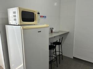 a microwave sitting on top of a refrigerator at Studio mobiliado na Vila Guilherme - São Paulo/SP in São Paulo