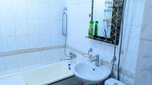 a white bathroom with a sink and a bath tub at Apartments in the center in Taraz
