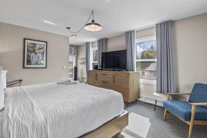 a bedroom with a bed and a flat screen tv at Lamphouse By Basecamp in Canmore