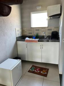 eine Küche mit weißen Schränken, einem Waschbecken und einem Fenster in der Unterkunft FLATS SETE ESTRELAS DO MAR in Ilhéus