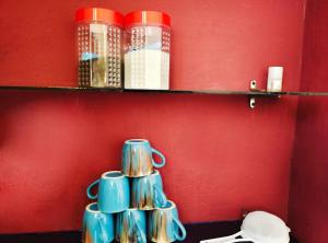 a shelf with cups and books on a red wall at Mannat Inn Homestay (Mysore) in Mysore