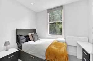 ein weißes Schlafzimmer mit einem Bett und einem Fenster in der Unterkunft Hackney Suites in London