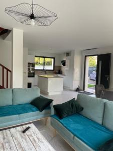 a living room with two blue couches and a kitchen at Maison Bijou 3 chambres à 10min de DisneyLand Paris in Chalifert +13 photos