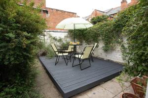 una mesa y sillas en una terraza de madera con sombrilla en *Cosy home with parking for you* en Derby