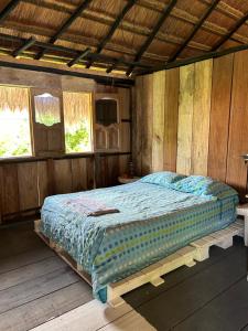 een slaapkamer met een bed in een houten kamer bij Eco Hostal Villa Canada - A Sustainable Oasis on Isla de Tierra Bomba in Playa Punta Arena