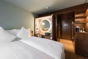 ein Schlafzimmer mit einem großen weißen Bett und einem Spiegel in der Unterkunft Hotel Aare Thun in Thun