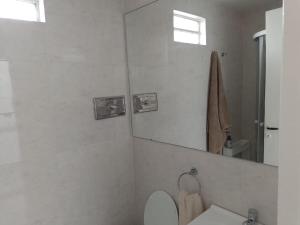 y baño con aseo blanco y espejo. en Lovely one bedroom apartment in Vicente Lopez en Vicente López