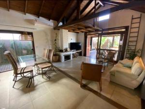 een woonkamer met een glazen tafel en stoelen bij Aconchegante e charmosa casa in Garopaba