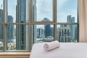 a bed with a towel on it in front of a window at BellaVista - Spectacular - 2 BR Penthouse - Boulevard Central - Panoramic Terrace & Burj Khalifa View in Dubai +24 photos