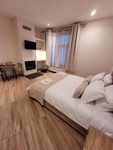 una camera da letto con un grande letto bianco e una televisione di Kleodora Apartments ad Aráchova