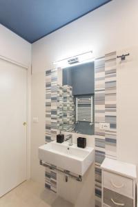 ein weißes Badezimmer mit einem Waschbecken und einem Spiegel in der Unterkunft Frangipane 31 Monti Terrace in Rom