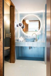 ein blaues Badezimmer mit einem Waschbecken und einem Spiegel in der Unterkunft Hotel Aare Thun in Thun
