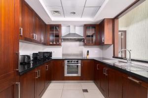 a kitchen with wooden cabinets and a stove top oven at Bellavista - High Floor - 1BR - 29 Boulevard - Burj Khalifa & Fountain View in Dubai