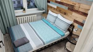 1 cama con almohadas azules y blancas y ventana en APARTAMENT "Opawska Przystań", en Głuchołazy