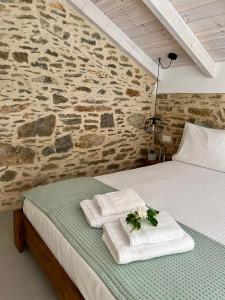 1 dormitorio con 1 cama con toallas y pared de piedra en Katrani studios, en Symi